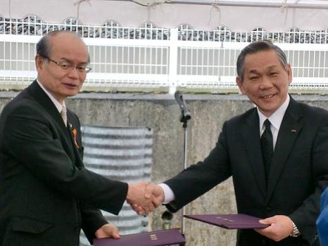 橋川市長とコカ・コーラウエスト（株）夏原京滋営業部長が握手をしています