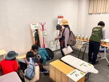 リユース家具抽選会の風景。ステージ上にリユース家具が並べられ、ステージしたのは抽選箱がおかれている。