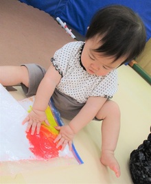 袋に入った絵具を手で揉んで混ぜるこどもの写真