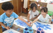 複数の青色の絵具で描くこどもたちの写真