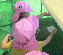 滴り落ちる水を容器で受け止めるこどもの写真
