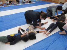 長く広げたロール紙の上で寝転がるこどもたちの写真