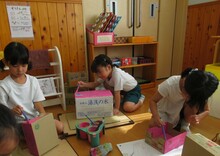 空き箱を開いて工作するこどもたち