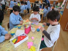 机の上で、花飾りを作るこどもたちのようす