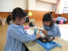 机の上で工作をして遊ぶこどもたちのようす
