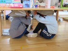 机の下にもぐって頭を守っています