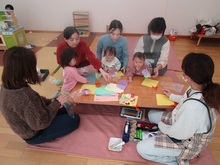 机の上でひな飾りの製作をする親子のようす