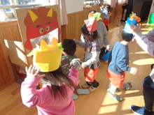 段ボールで作った鬼さんの口へ新聞の豆を入れています。