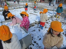 たくさんの雪が園庭につもり、雪を集めて遊んでいます。
