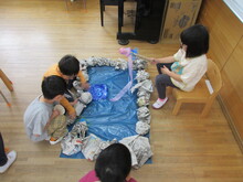 ブルーシートの上で魚釣りのごっこ遊びをしているようす