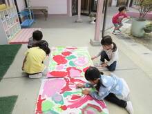 床の上に敷いた大きな紙の上に、絵具で絵を描いているようす