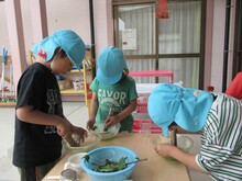 タライに植物を入れ、道具を使ってつぶしているこどもたち