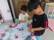 机の上で、色水を混ぜて遊ぶこどもたち