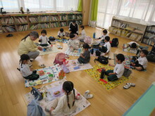 屋内でレジャーシートを敷きお弁当を食べるこどもたち