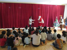 ステージ上に登場したサンタクロースを見上げるこどもたち