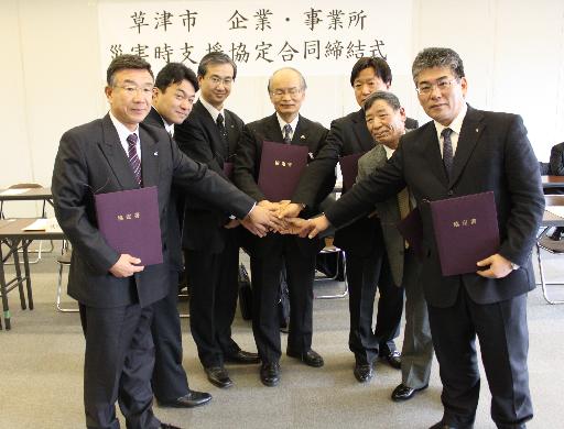 災害協定締結式で、市長と各事業所の代表者全員が握手をしている写真です。
