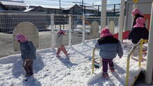 雪の積もった園庭を歩きまわるこどもたちのようす