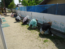 草むしりのため座って作業する人々の写真