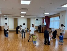 室内で立ち上がり、リトミックあそびをする親子の写真