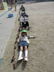 収穫したイモと並ぶこどもたちの写真