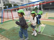 サツマイモのツルを使って電車ごっこをするこどもたちの写真