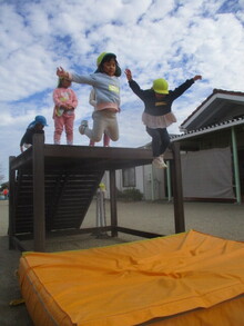 遊具からマットへジャンプするこどもたちの写真