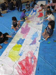 絵具を塗り広げるこどもたちの写真