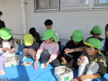 ブルーシートの上でイモを味わうこどもたちの写真