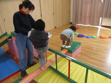 大人に支えられながら、巧技台を慎重に歩くこどもたちの写真