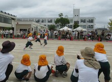 運動会で走るこどもたちを見るこどもたちの写真