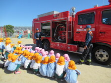 消防車の前に集まって話を聞くこどもたちの写真