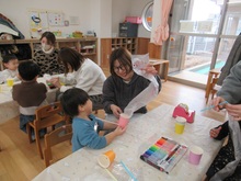 紙コップにナイロン袋を組み合わせ、工作をするこどもの写真