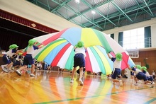 パラバルーンを持ち上げて演技をするこどもたちの写真