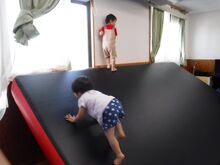 傾斜のある特大マットをこどもが登っている様子