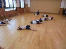 屋内で床の上にあおむけになり体を動かすこどもたちの写真