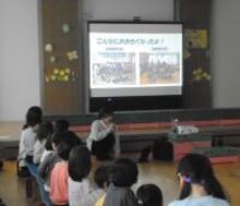 スクリーンに投影されたスライドを見上げるこどもたち