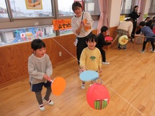 友だちと協力して、風船をうちわでパタパタして動かします