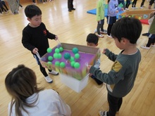 穴にボールを落とそうと友だちと協力しています