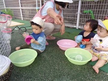 たらいに張った水であそぶこどもたちの写真