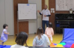 ホワイトボードを見上げる保護者とこどもたちの写真