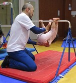 保護者に支えられながら鉄棒で回転する子どもの写真