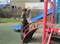 保護者と遊具で遊ぶこどもの写真