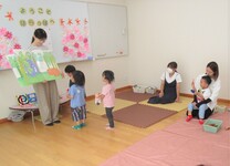 屋内で絵本の読み聞かせを聞くこどもたちの写真