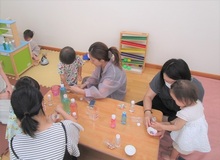 ボトルに入った色水で、センサリーボトルを作っている親子の写真