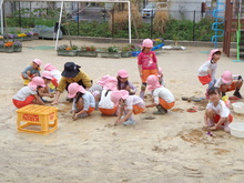 5歳児が雨上がりの園庭で泥んこ遊びをしています。