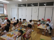 テーブルに並ぶ給食とこどもたちの写真