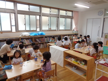 テーブルに並べられたおやつとこどもたちの写真
