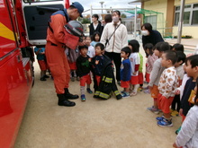 園児が消防服を着せてもらっています。