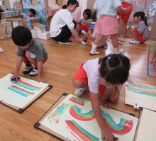 スポンジにカラフルな色の絵具を含ませて画用紙に虹を描いています。