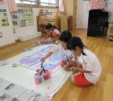 大きな模造紙にふでに絵具を付けて走らせています。